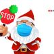 Cute santa claus wearing a surgical protective face mask and holding a stop sign with green virus cells.